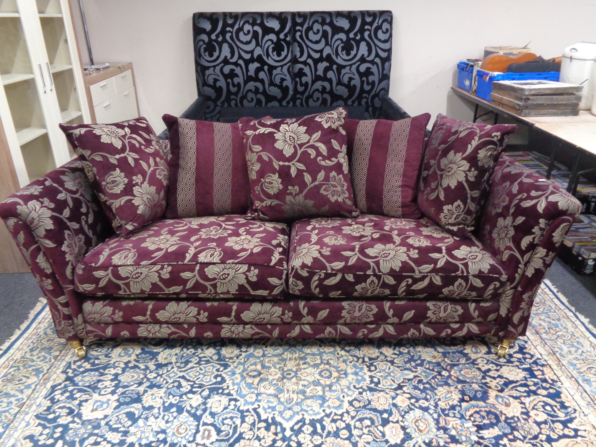 A contemporary settee upholstered in a Burgundy and silver floral fabric with scatter cushions.