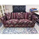 A contemporary settee upholstered in a Burgundy and silver floral fabric with scatter cushions.