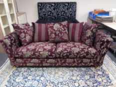 A contemporary settee upholstered in a Burgundy and silver floral fabric with scatter cushions.