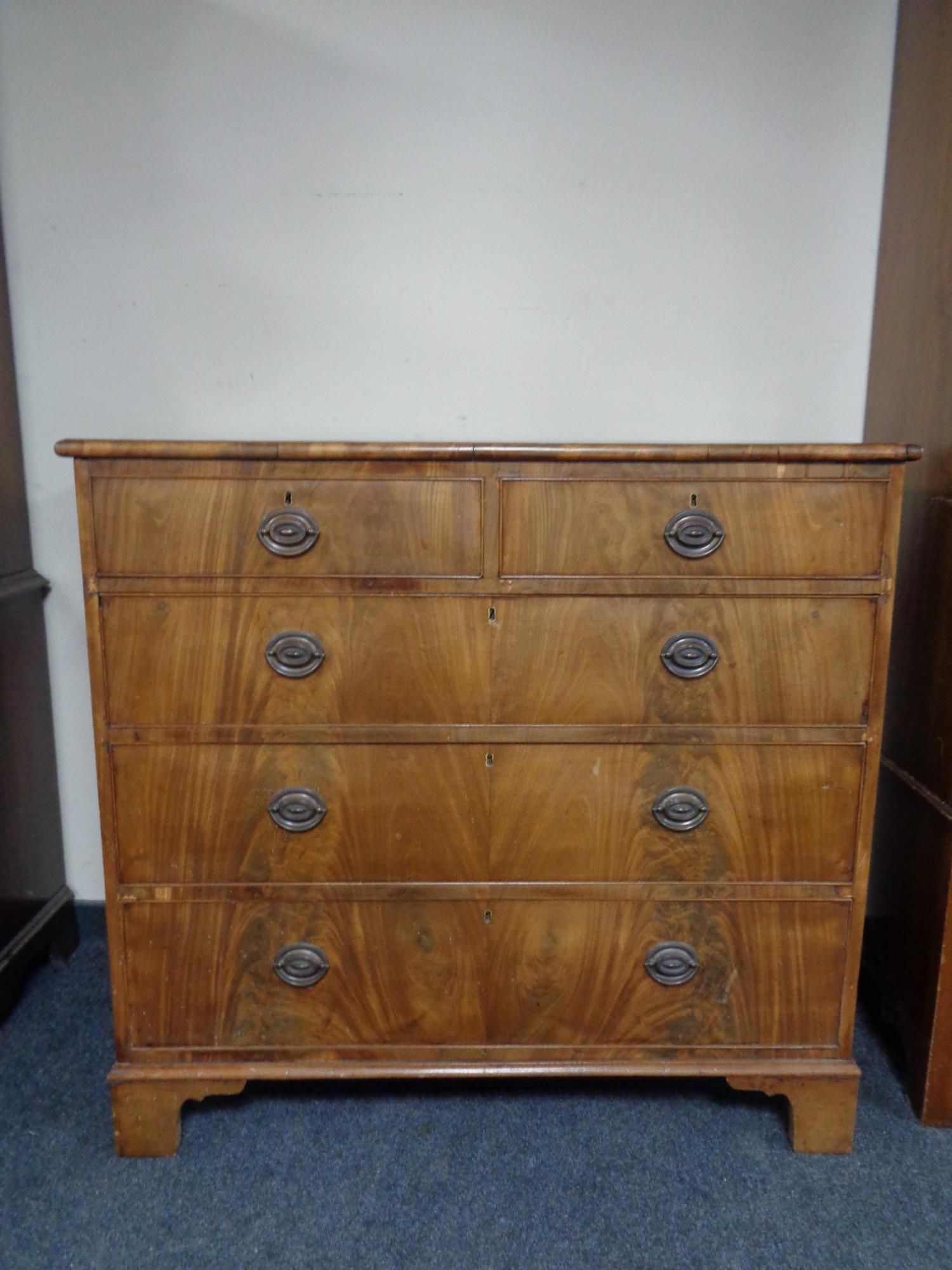 A George III style mahogany five drawer chest on bracket feet