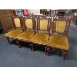 A set of four late 19th century carved oak dining chairs upholstered in a gold brocade fabric.
