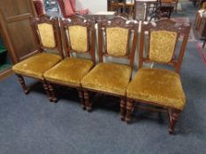 A set of four late 19th century carved oak dining chairs upholstered in a gold brocade fabric.