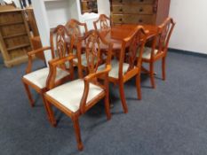 An oval inlaid yew wood twin pedestal dining table together with a set of six shield back chairs,