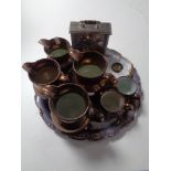 A silver plated tray containing six copper lustre tankards and jugs,