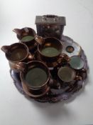 A silver plated tray containing six copper lustre tankards and jugs,