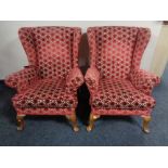 A pair of 20th century wing back armchairs re-upholstered in a red and cream fabric.