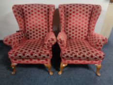 A pair of 20th century wing back armchairs re-upholstered in a red and cream fabric.