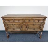 An Edwardian oak double door sideboard, fitted two drawers on barley twist legs.