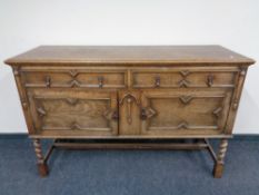 An Edwardian oak double door sideboard, fitted two drawers on barley twist legs.