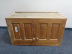 A pine double door wall cabinet.