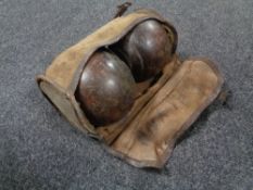 A pair of vintage wooden lawn bowls in a cloth bag.