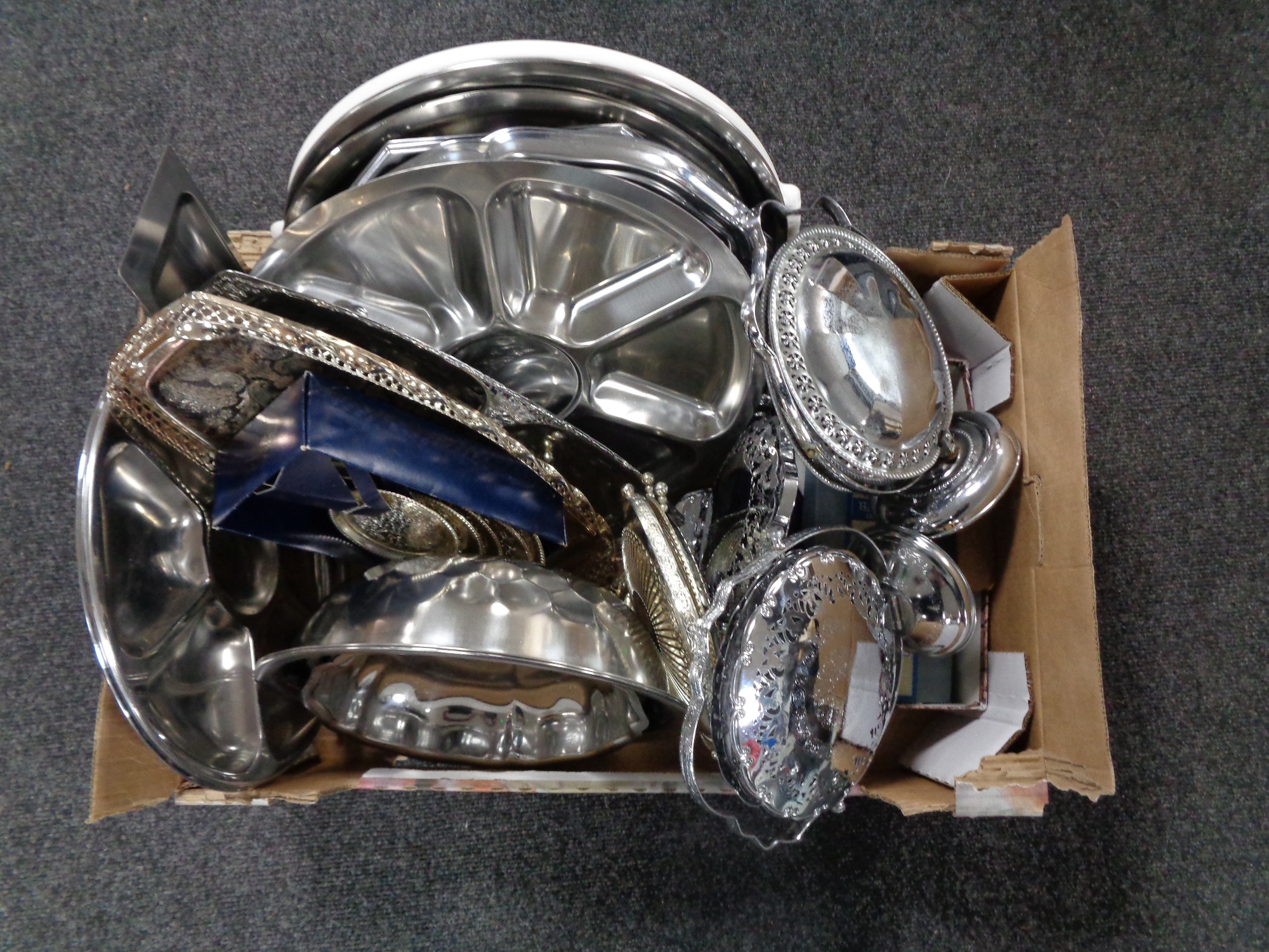 A box containing stainless steel serving trays, bowls etc,