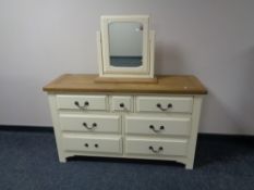 A contemporary cream seven drawer dressing chest with oak top and mirror