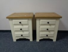 A pair of contemporary cream three drawer bedside chests with oak tops