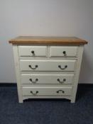 A contemporary cream five drawer chest with oak top