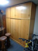 A 20th century teak four-door sliding wardrobe fitted with cupboards above
