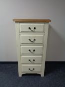 A contemporary cream narrow five drawer chest with oak top