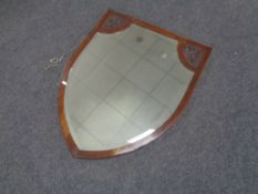 An Edwardian mahogany shield-shaped bevelled mirror with poker work panels.