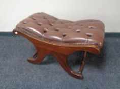 A brown buttoned leather upholstered footstool on X-framed support