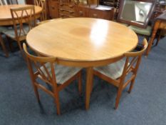 A circular teak G-plan extending dining table together with three chairs