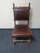 An oak ecclesiastical style chair upholstered in buttoned leather on X-frame