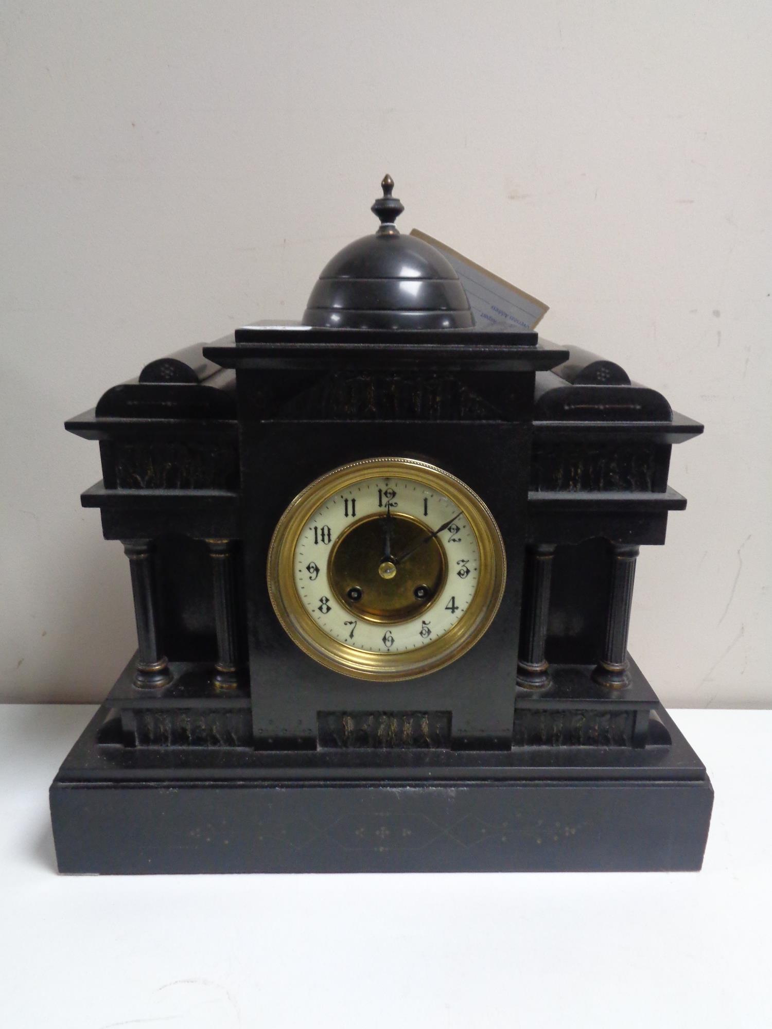 A 19th century German black slate half hour striking mantel clock with brass and enamel dial and