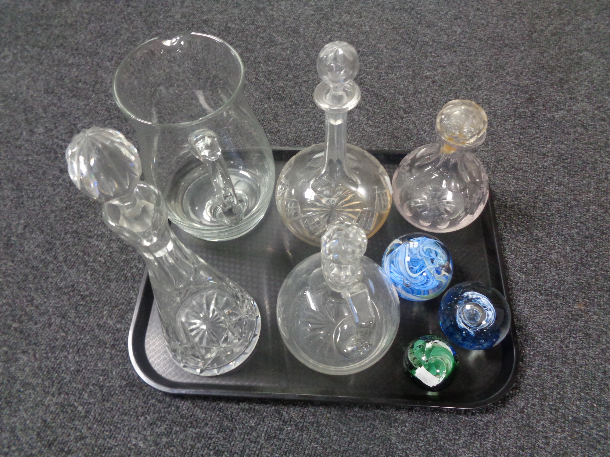 A tray containing antique and later glass decanters, glass jug together with three paperweights.