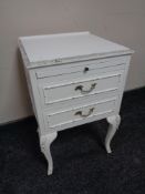 A white and gilt two drawer bedside table with slide