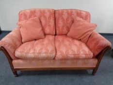 A pair of wooden framed settees in pink fabric
