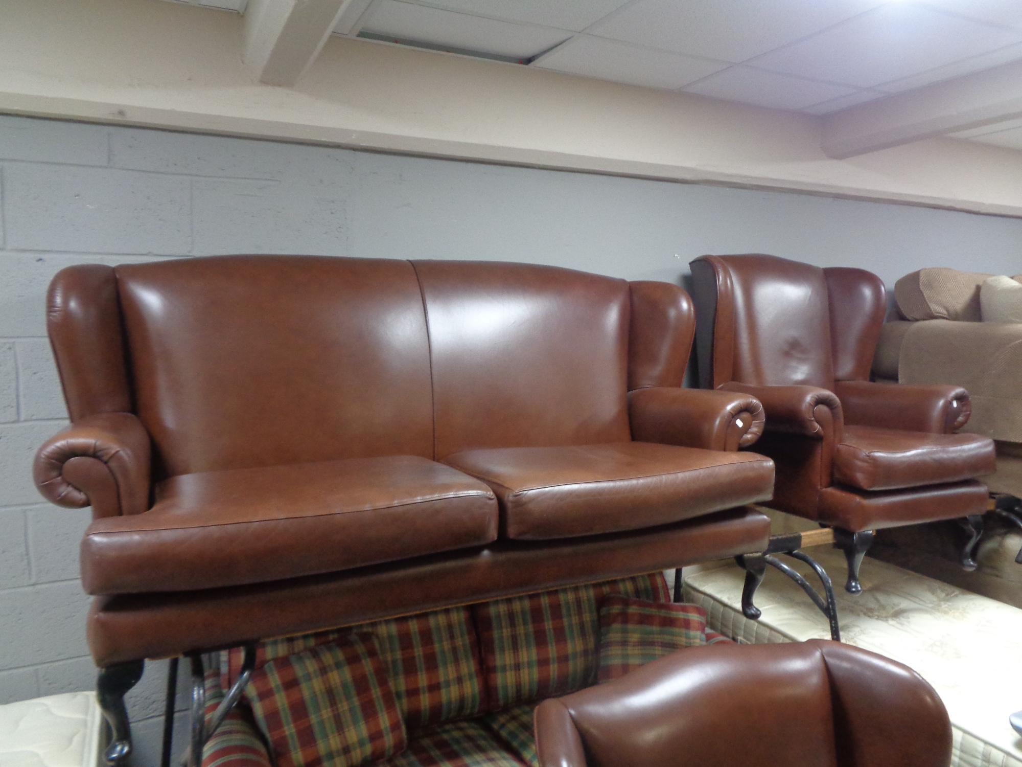 A brown leather three piece lounge suite comprising of wing backed settee and pair of armchairs
