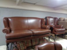 A brown leather three piece lounge suite comprising of wing backed settee and pair of armchairs