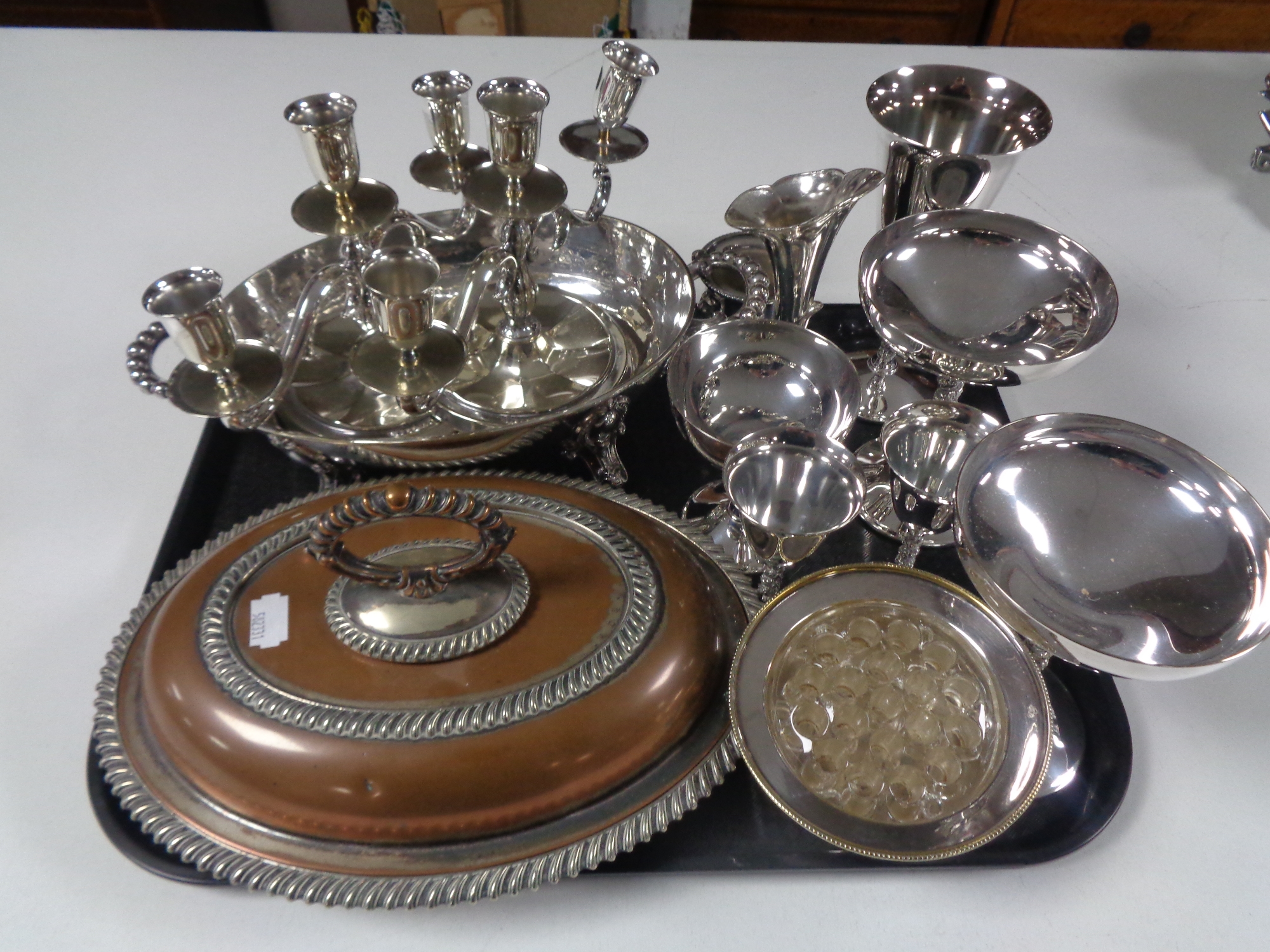 A tray containing plated wares to include terrenes, pair of three way candlesticks, goblets etc.