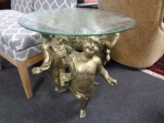 A contemporary glass topped occasional table on cherub base