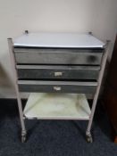 A metal medical trolley fitted with three drawers