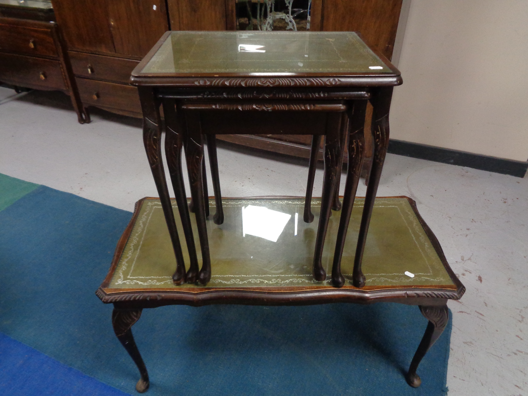 A mahogany glass topped leather topped coffee table together with a nest of three matching tables