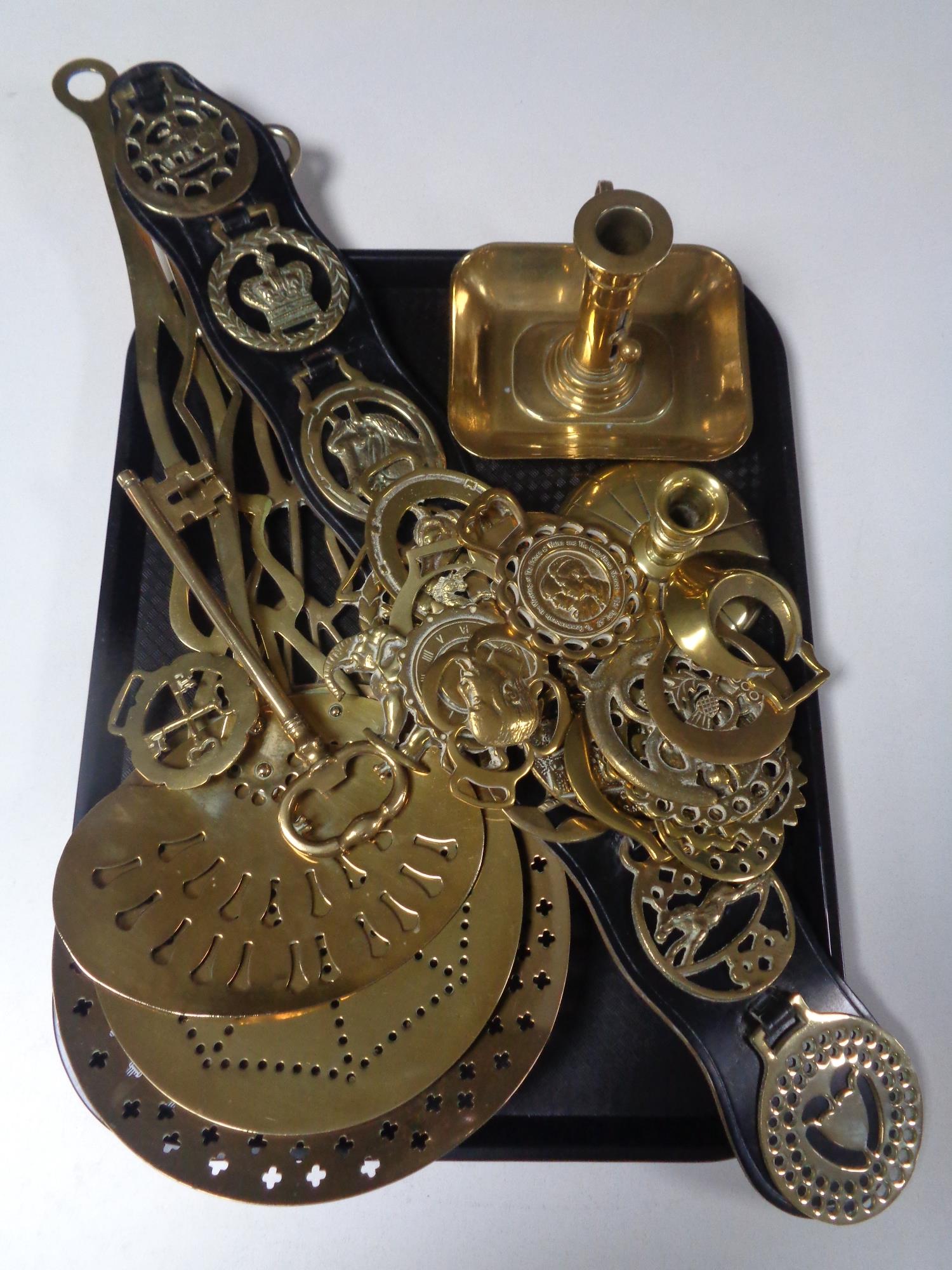 A tray containing assorted brass ware to include horse brasses, a brass key candlestick,