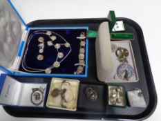 A tray of silver and costume jewellery including locket on chain, enamelled badges,