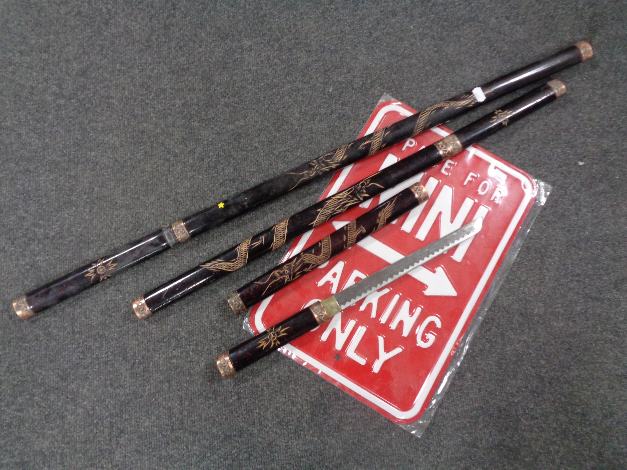 Three graduated Japanese style swords together with a metal parking sign.