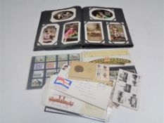 An early 20th century postcard album of greetings cards and small quantity of stamps,