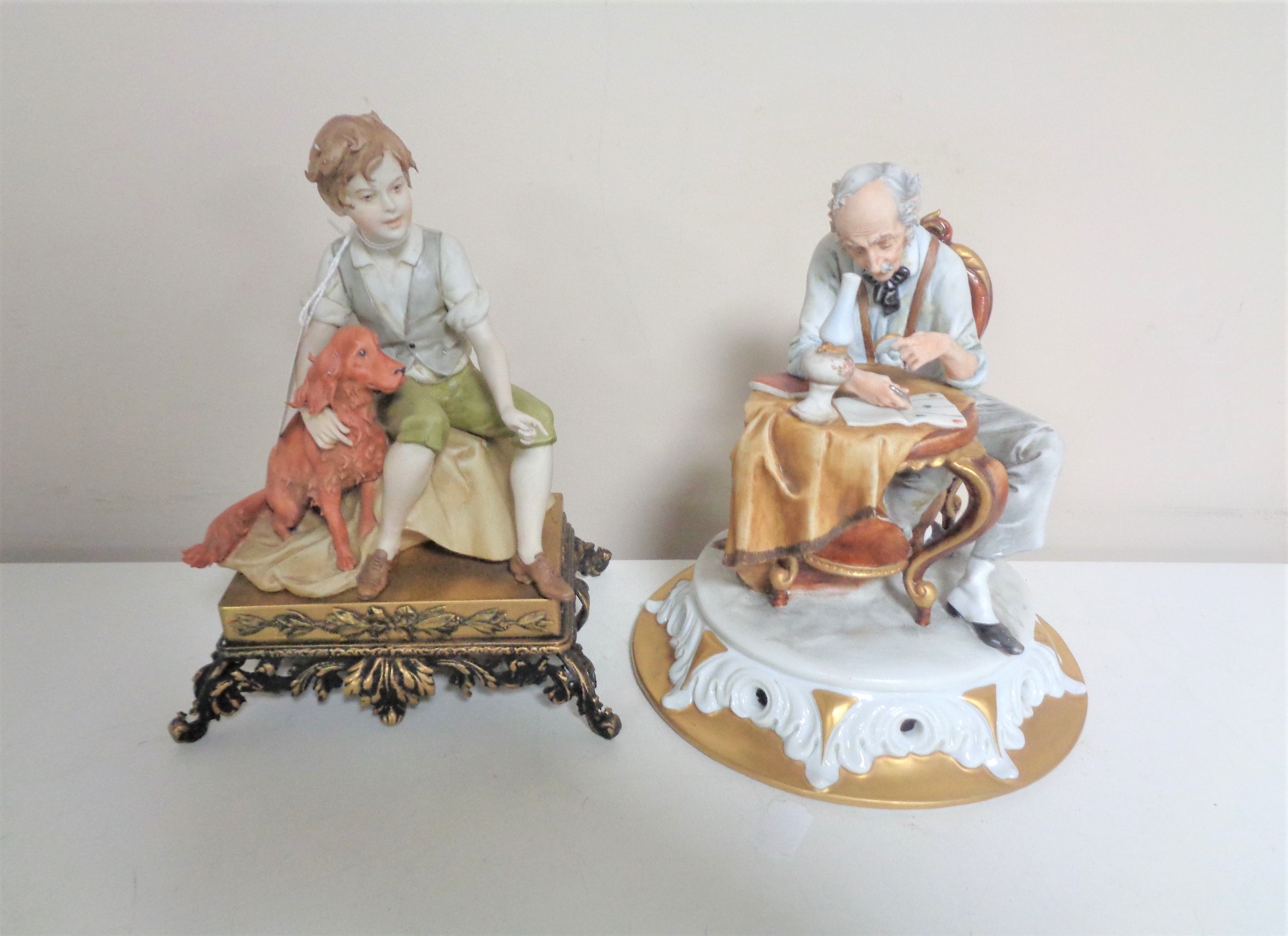 Two Italian Capodimonte figures - boy seated with red setter and man seated at table