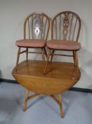 An Ercol elm and beech drop leaf kitchen table together with a pair of chairs