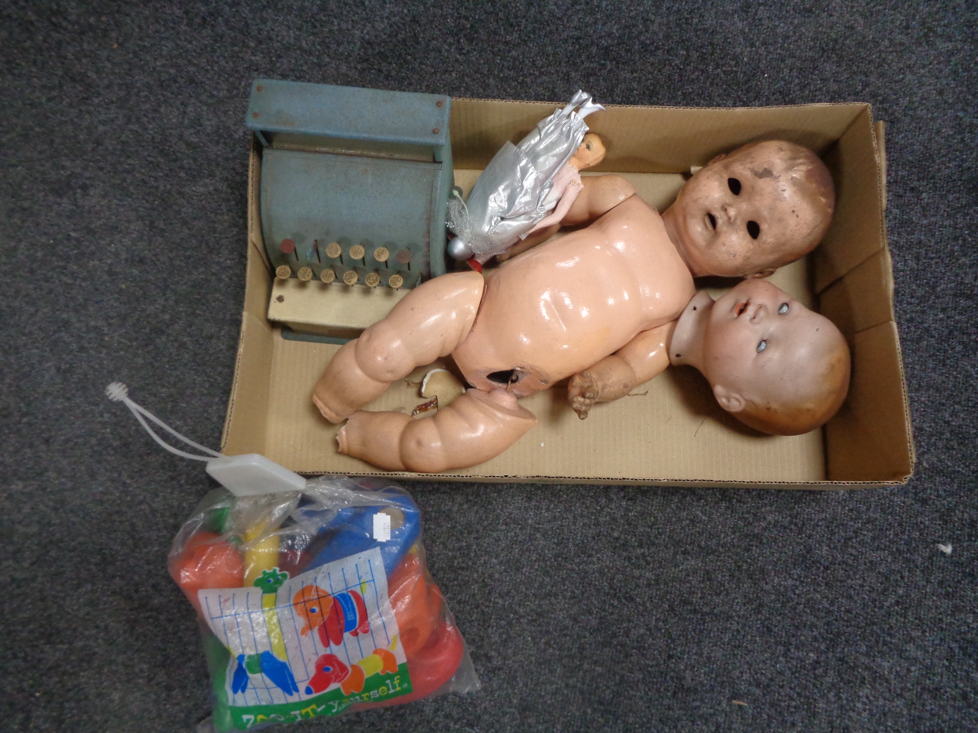 A box of vintage children's toys to include a Codeg cash register, doll's head, plastic doll,