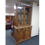 An oak Arts and Crafts double door bookcase, fitted cupboards and drawers beneath.