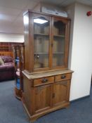 An oak Arts and Crafts double door bookcase, fitted cupboards and drawers beneath.