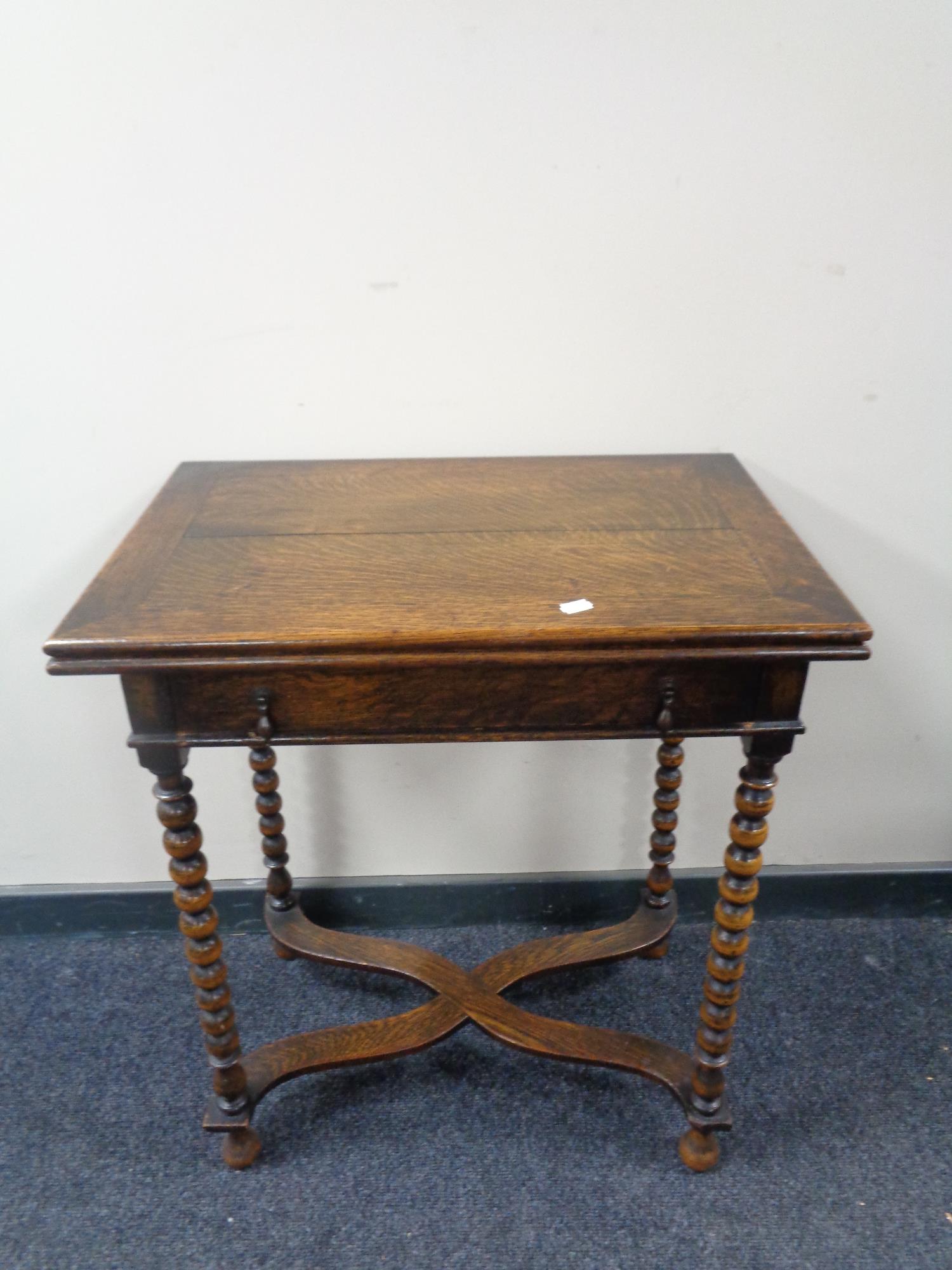 An Edwardian oak turn over top table fitted a drawer on bobbin legs