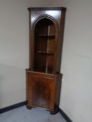 A mahogany corner cabinet fitted shelves and cupboard beneath