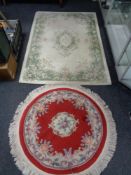 A circular red Chinese fringed rug together with a further floral rug on cream ground