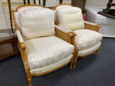 A pair of contemporary beech framed bergere armchairs upholstered in a Regency striped fabric