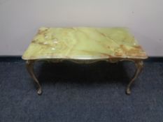 A shaped onyx topped coffee table on ornate brass base