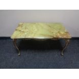 A shaped onyx topped coffee table on ornate brass base